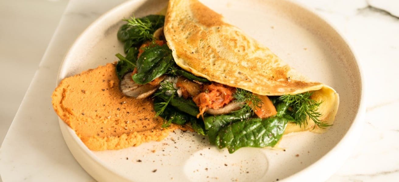 Golden brown omelette folded on a white plate, garnished with fresh herbs